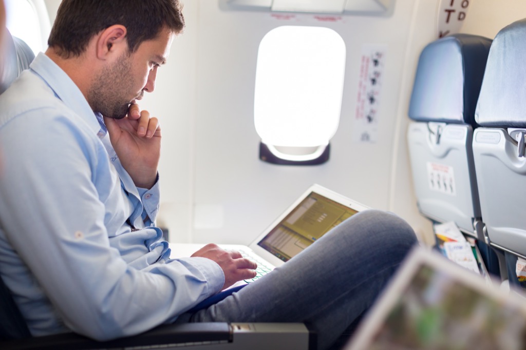 hombre trabajando en una laptop en un avión